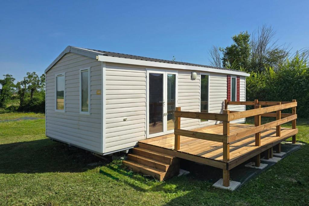 a white tiny house with a porch and a deck at Parc St Vincent in La Celle-sous-Gouzon