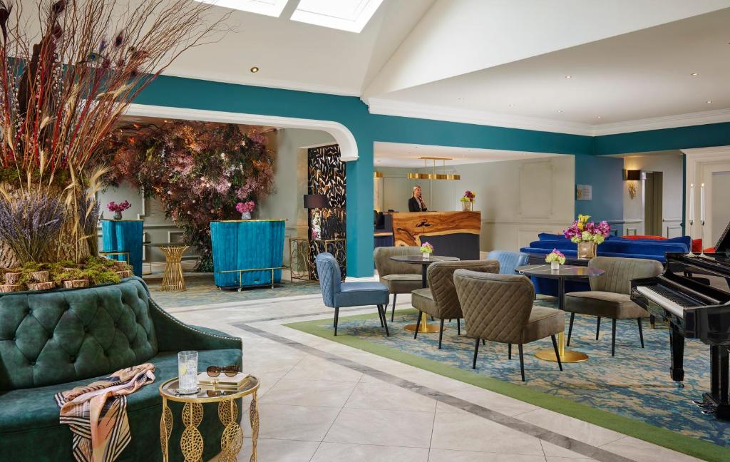 a living room with a green couch and a piano at Fitzgeralds Woodlands House Hotel in Adare
