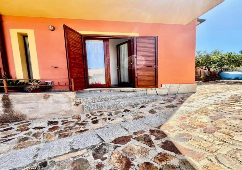 an orange house with a stone walkway next to a building at Casa Lucia in Villasimius