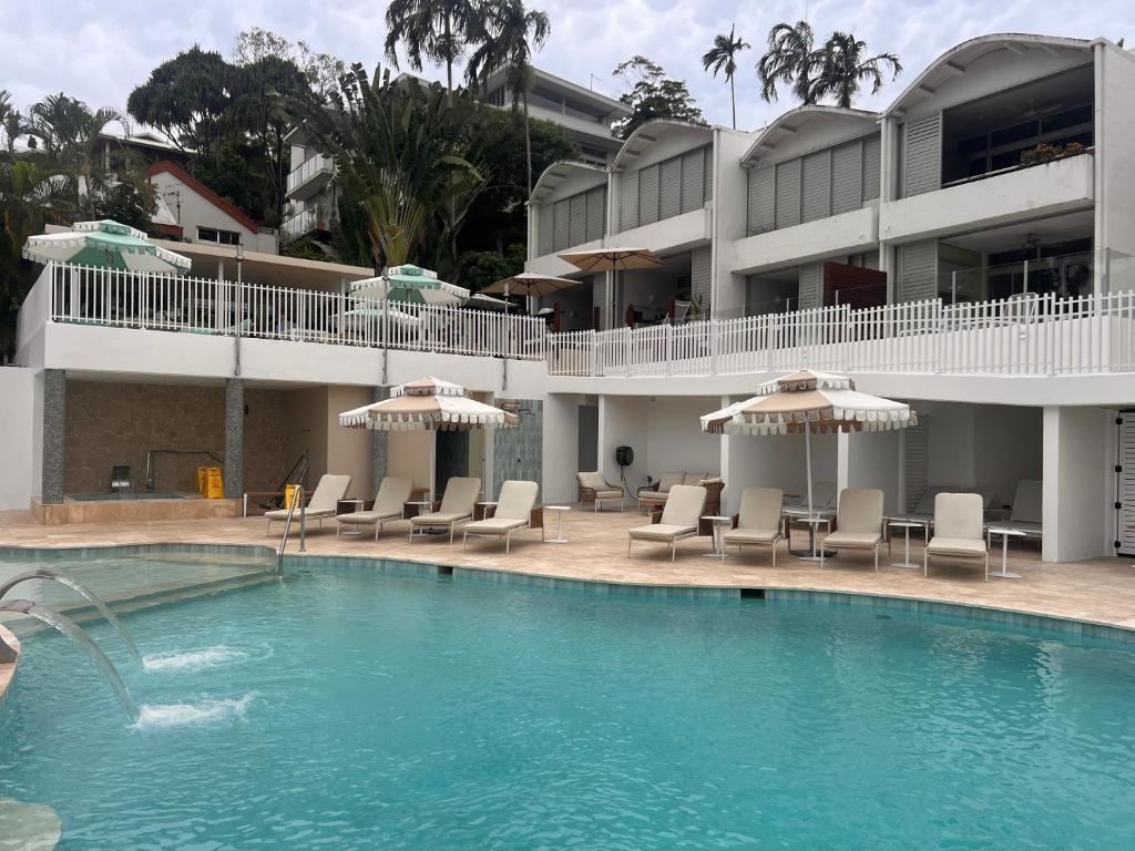 a swimming pool with chairs and umbrellas in front of a hotel at Port Douglas Penthouse Suite in Port Douglas