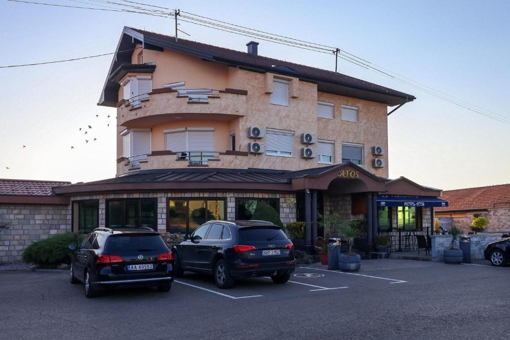 two cars parked in a parking lot in front of a building at Motel Atos in Laktaši