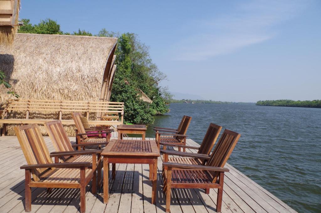 um grupo de cadeiras e uma mesa numa doca junto à água em Bamboo Bungalow em Kampot