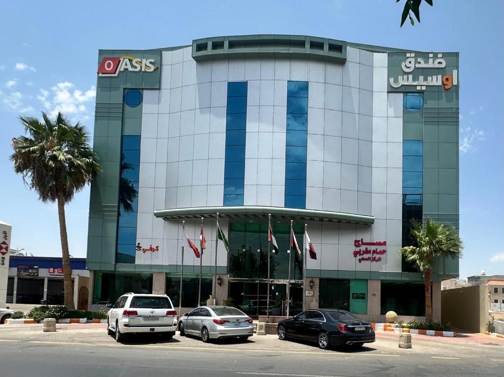 a building with cars parked in a parking lot at فندق روز أوسيس - Roz Oasis Hotel in Najran