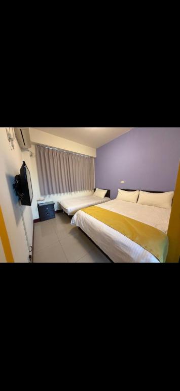 a hotel room with two beds and a television at 浮雲澗民宿 in Hu-hsia