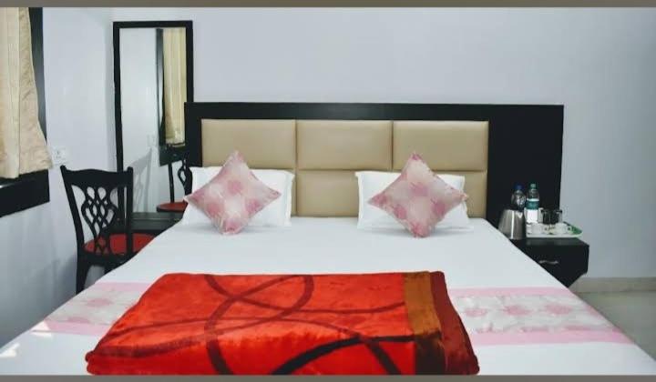 a bedroom with a large white bed with pink pillows at Karma Bodhgaya in Bodh Gaya