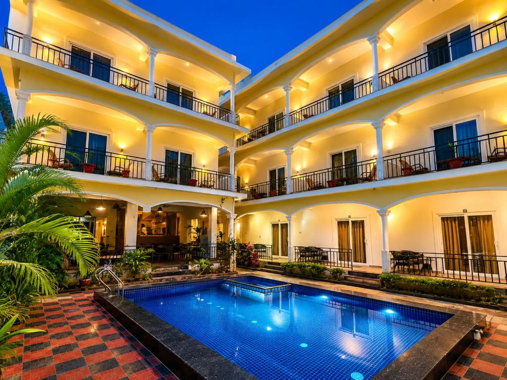 a hotel with a swimming pool in front of a building at Morjim Sunset Guesthouse- Apartments with Kitchen & AC Rooms in Morjim