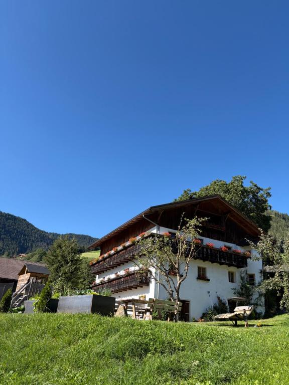 a white building with a brown roof in a field at Pardellerhof Lüsen in Luson