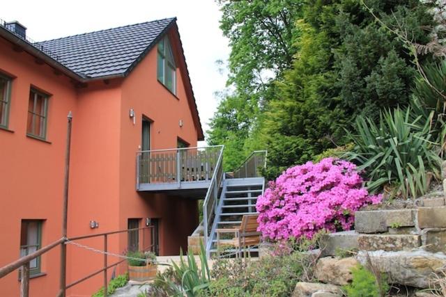 a house with a staircase and pink flowers in front of it at Haus Maja in Kurort Rathen