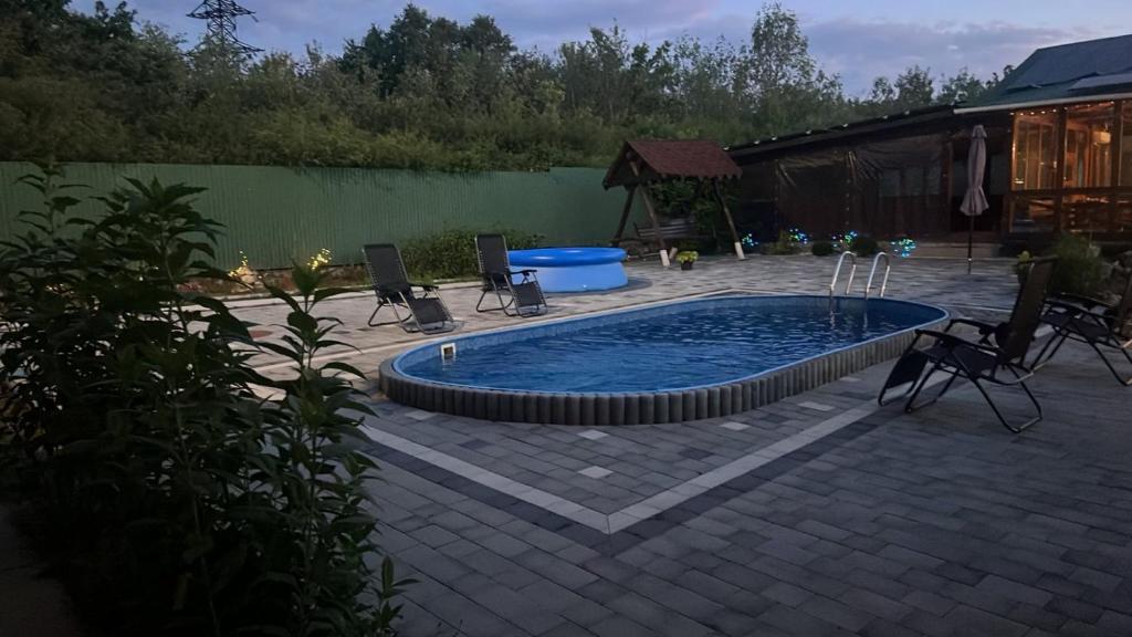 a swimming pool in a patio with chairs and a table at Ілона in Beregi