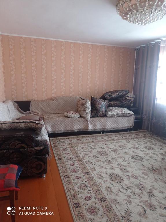 a living room with a couch and a rug at Гостевой дом Izat in Karakol