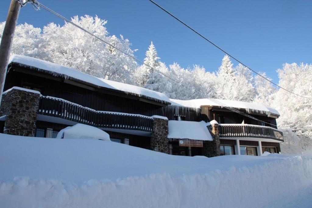 un edificio cubierto de nieve con una pila de nieve en Chalet Hotel Les Marmottes 2 étoiles NN, en Montferrier