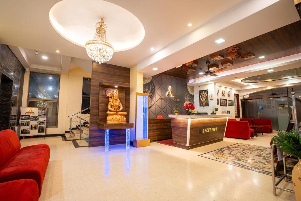 a lobby with a red couch and a statue in it at Ananya Comfortss in Hospet