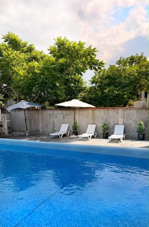 two white chairs and an umbrella next to a swimming pool at Modinakhe in Kobuleti