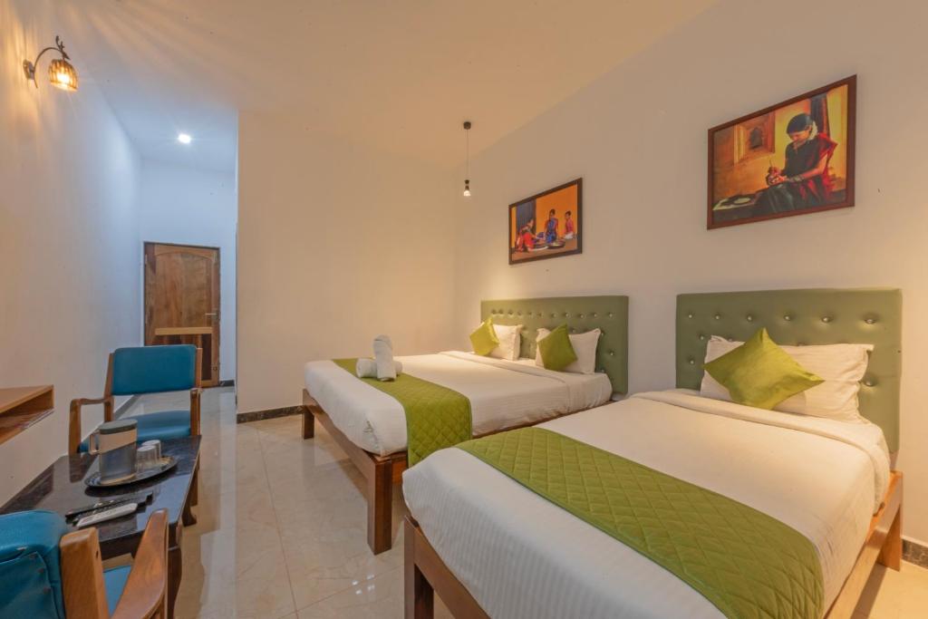 a hotel room with two beds and a desk at De Asian Resort in Pondicherry