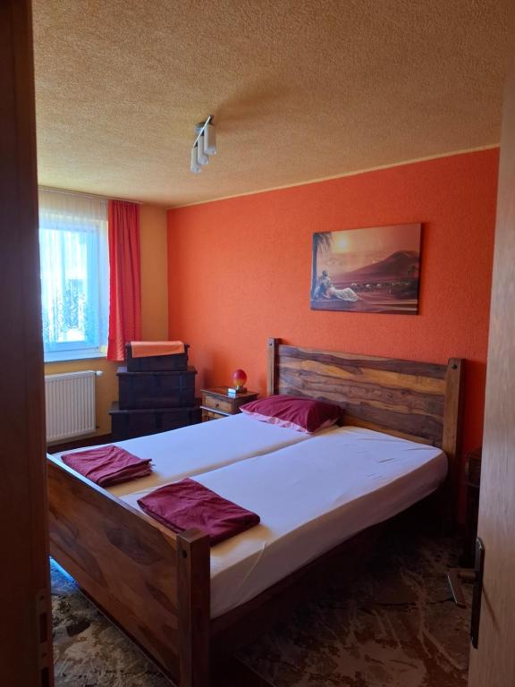 a bedroom with a large bed with an orange wall at Apartman National 2 in Velika Kladuša