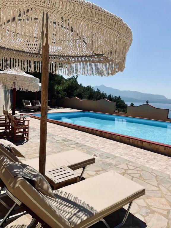 a view of a pool with chairs and an umbrella at Samos Panorama Hills in Pythagoreio