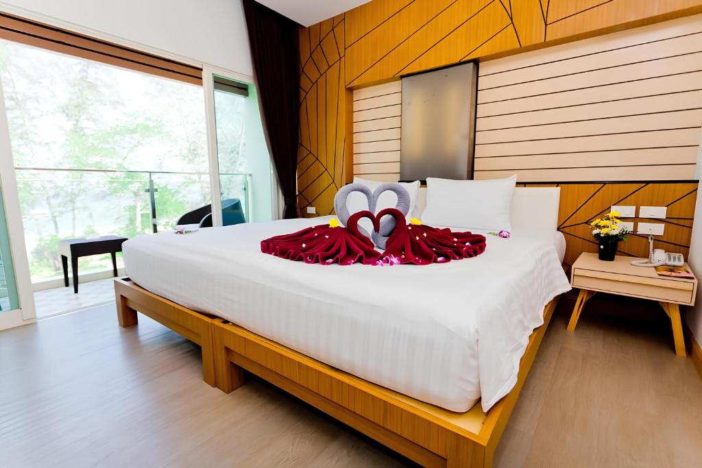 sypialnia z dużym białym łóżkiem i czerwoną sukienką w obiekcie Anda Beachside Hotel w mieście Karon Beach