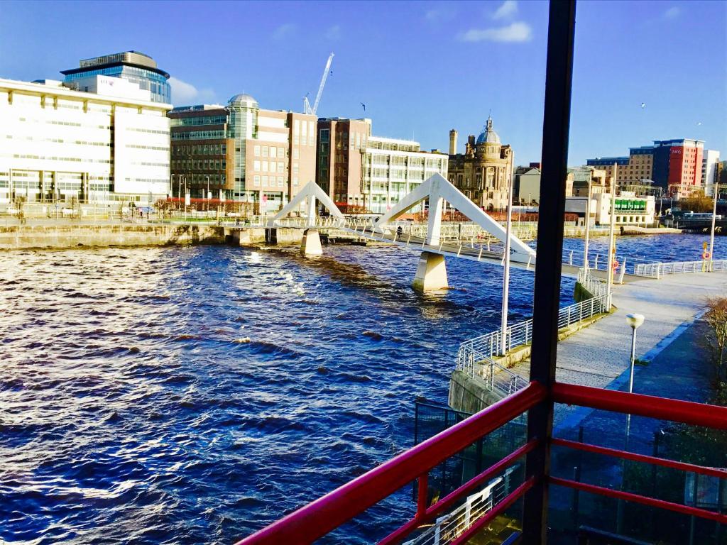 Glasgow City Centre Flat with River Views and Parking في غلاسكو: قارب على نهر مع جسر