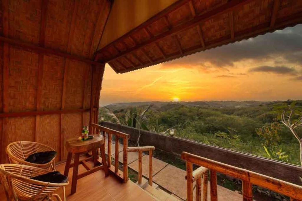 a room with a balcony with a view of a sunset at The Penida Angmas View in Nusa Penida