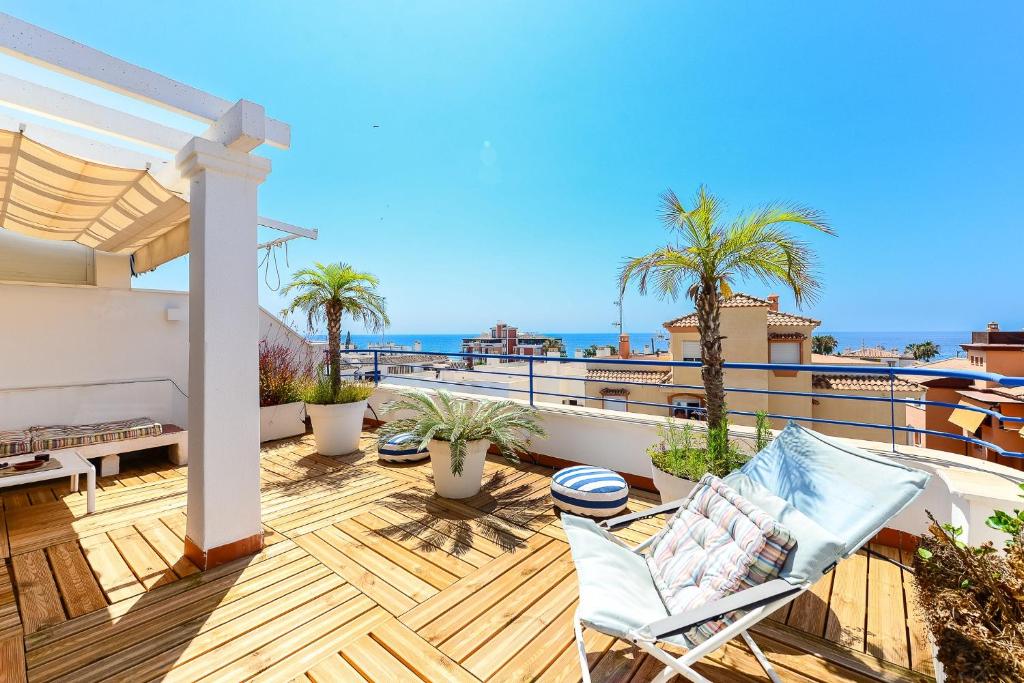 a balcony with chairs and palm trees and the ocean at Breathtaking Penthouse Las Azaleas in Torrox