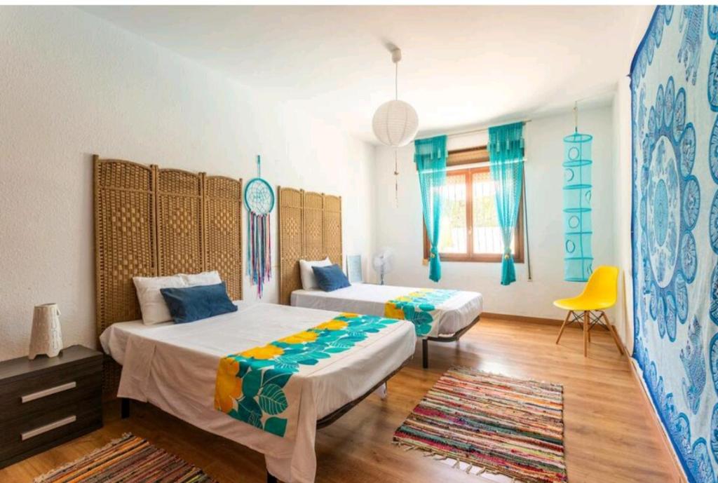 a bedroom with two beds and a yellow chair at CM Azibi Blue Room in El Campello