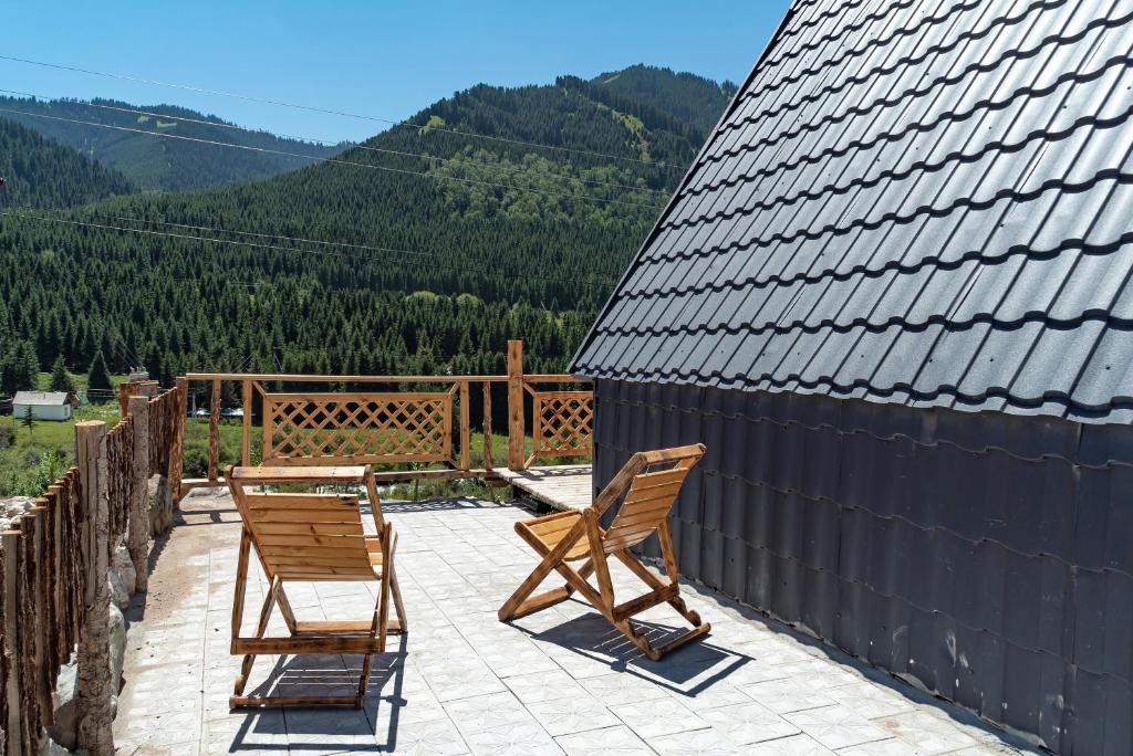 two chairs and a table on a patio with mountains at A-frame Sky in Karakol