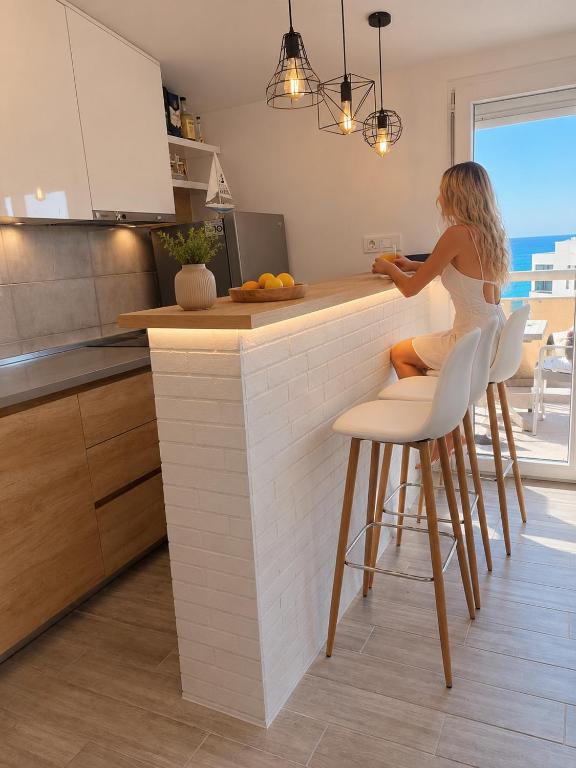 a woman sitting at a counter in a kitchen at VN Lux Apartments in Prijevor