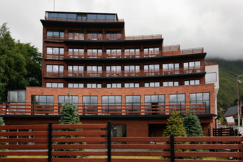 a large brick building with a large balcony at Lens Design Hotel in Kazbegi