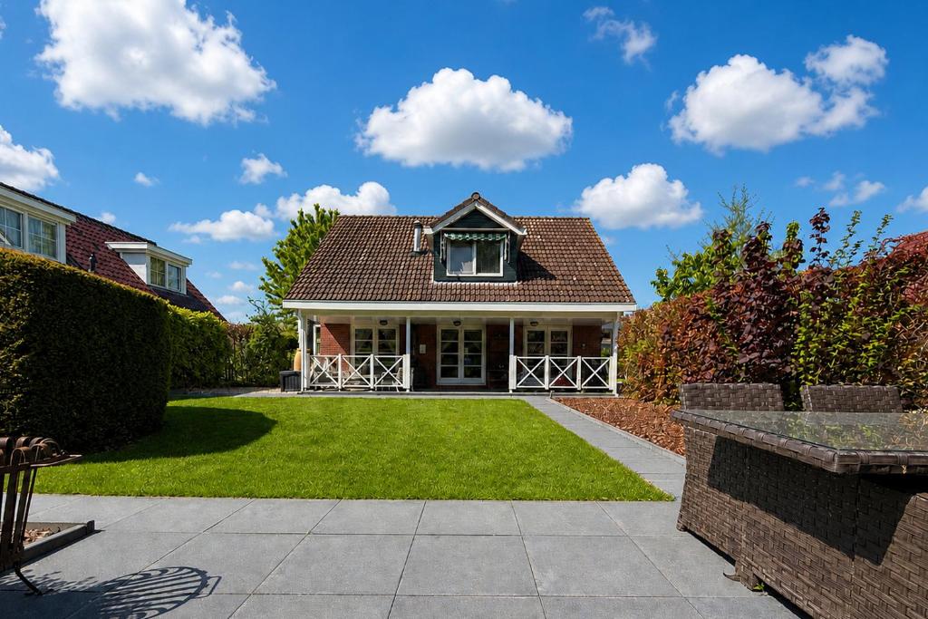 a house with a green yard with a house at The Cosy Cottage - Comfort Sauna & Hot Tub in Private Garden in Zeewolde