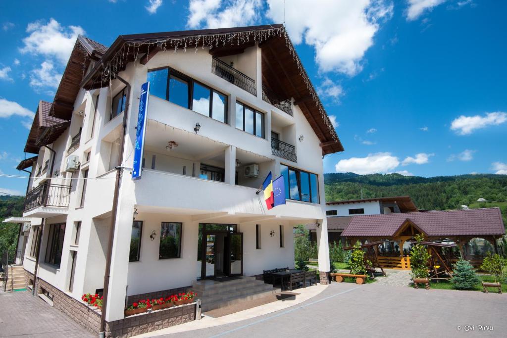 a large white building with blue shutters at Pensiunea Royal in Borşa