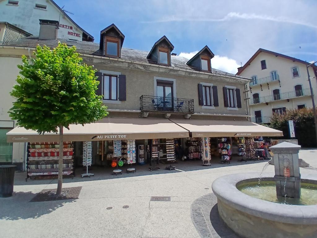 a building with a store with a tree in front of it at Le Som' des Pyrénées in Luz-Saint-Sauveur