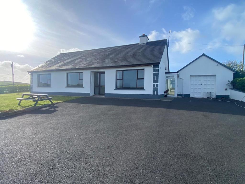 a white house with a picnic table in front of it at Farrihy Hill House in Doonbeg