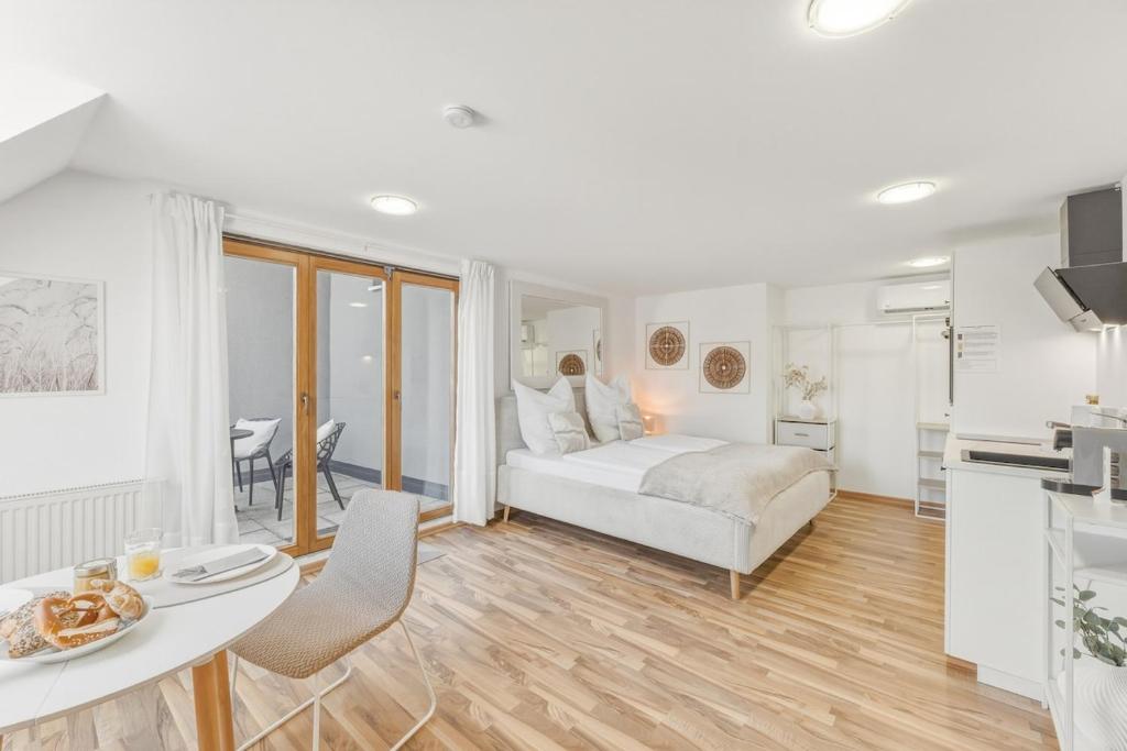 a white bedroom with a bed and a table and chairs at Scharnhäusle 6 - wunderschönes Apartment mit Balkon in Ostfildern