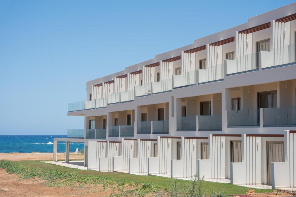 a building on the beach with the ocean in the background at Akanthus Pirgos Bay in Malia