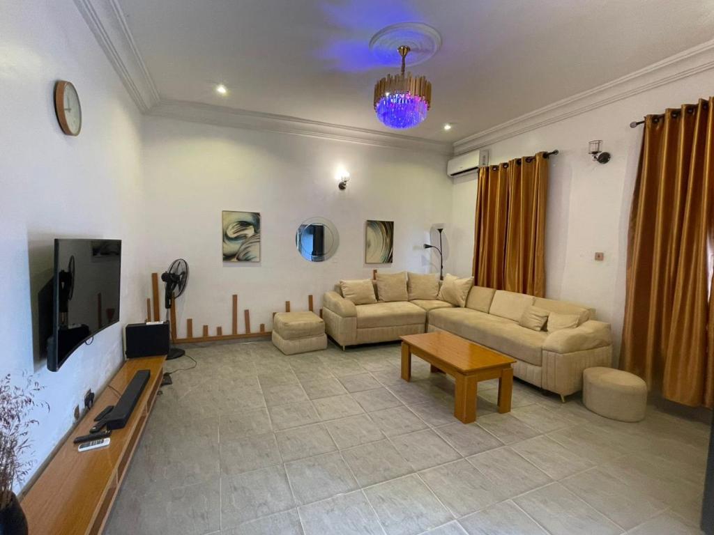 a living room with a couch and a tv at Pristine Apartment in Gwagalada