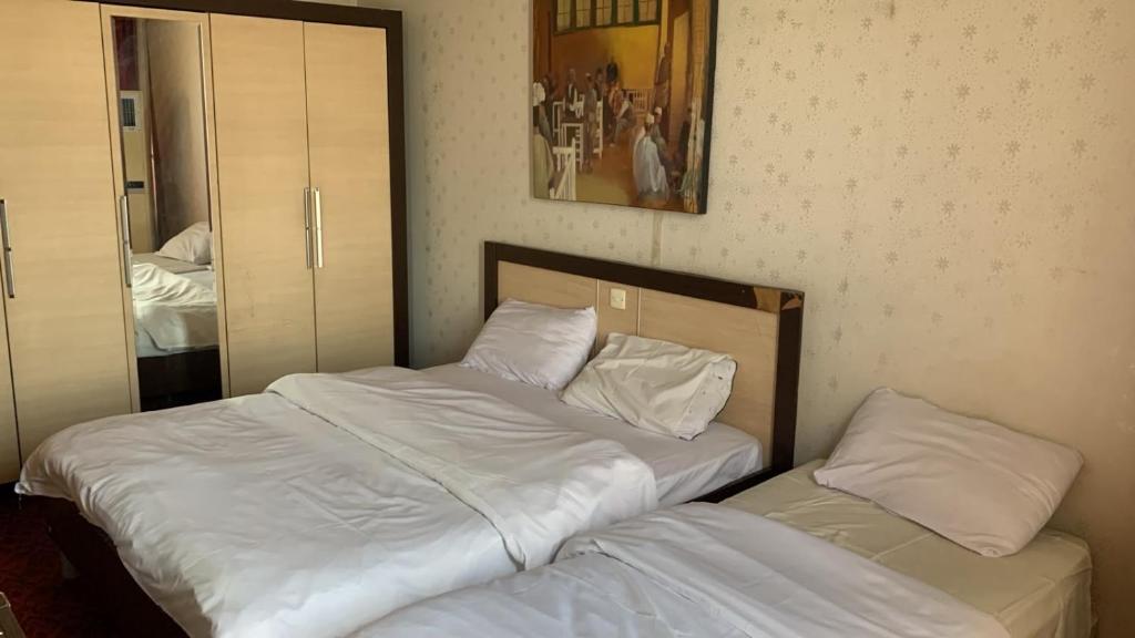 two twin beds in a bedroom with a mirror at Chwar chra hotel in Erbil