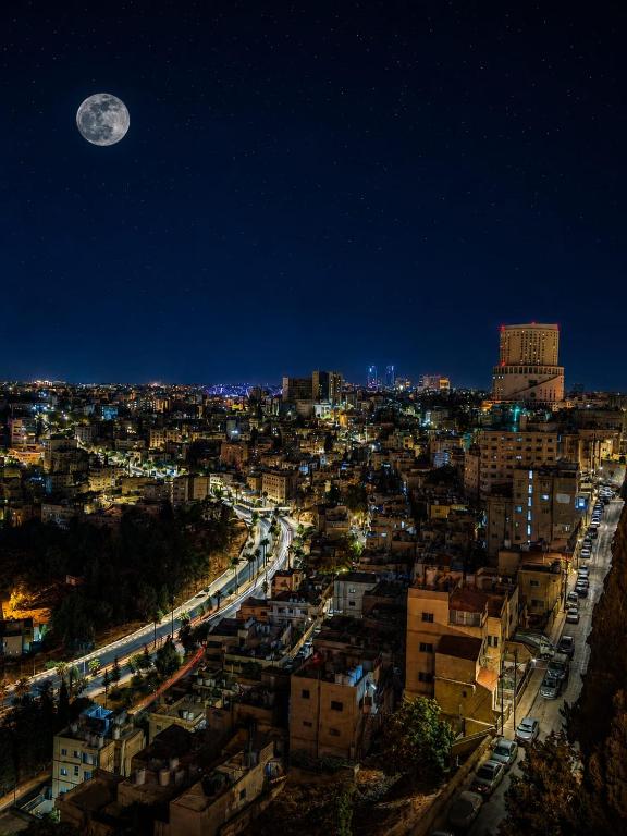 a view of a city at night with a full moon at Zaina Plaza Hotel in Amman