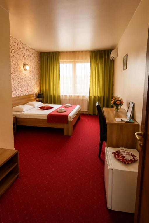 a hotel room with a bed and a desk at Hotel Olimp in Cluj-Napoca