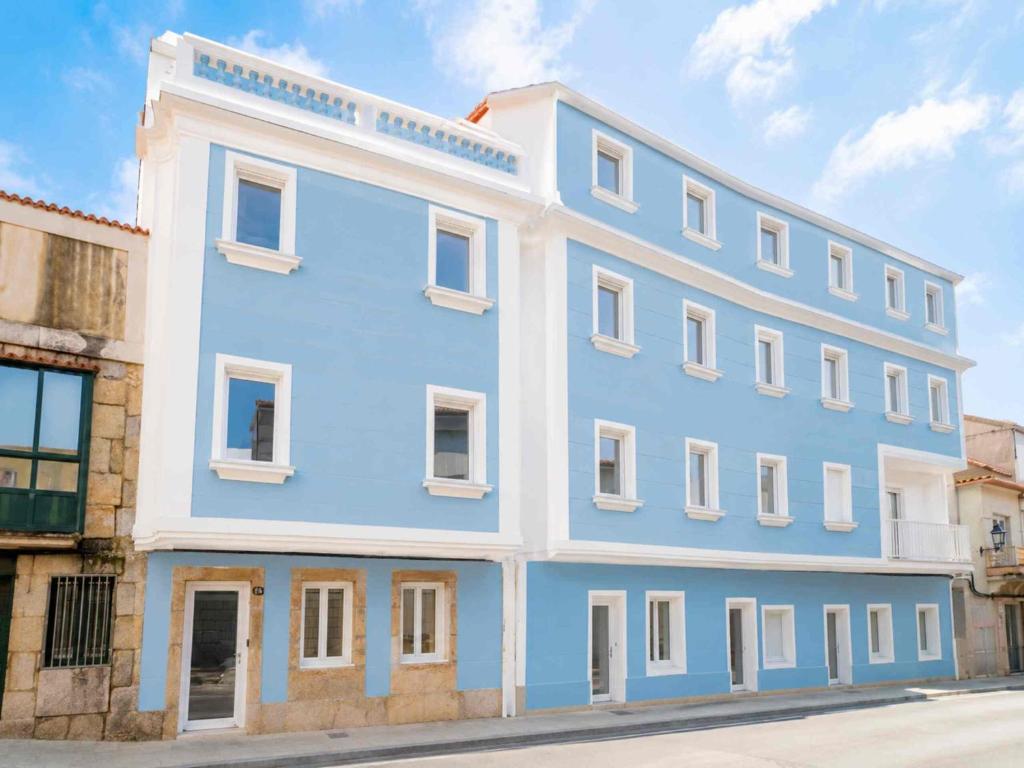 a blue building with white windows on a street at YBH Villa Lara in Villanueva de Arosa