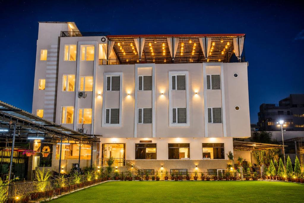 a large white building with a lawn in front of it at Hotel Bhairav Bagh -100 Mtr from Celebration Mall in Udaipur