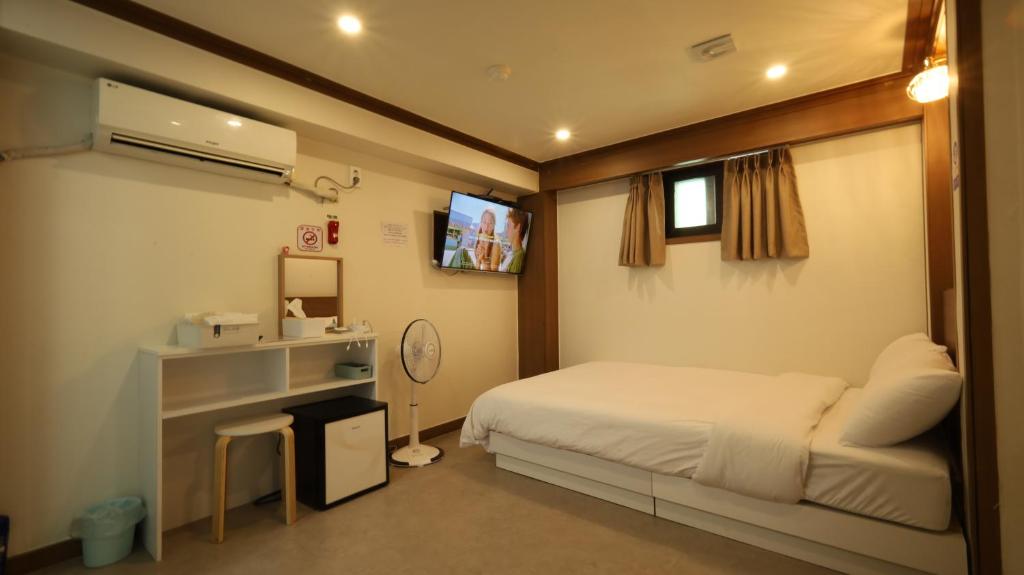 ein kleines Schlafzimmer mit Bett und Fernseher in der Unterkunft Dal Hotel in Seoul