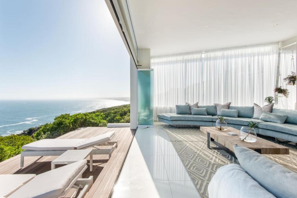 a living room with blue furniture and the ocean at White Water Retreat - Pinnacle Point in Mossel Bay