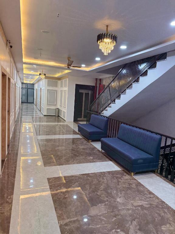 a lobby with blue couches and stairs in a building at Hotel Keshav Villa in Mandhana