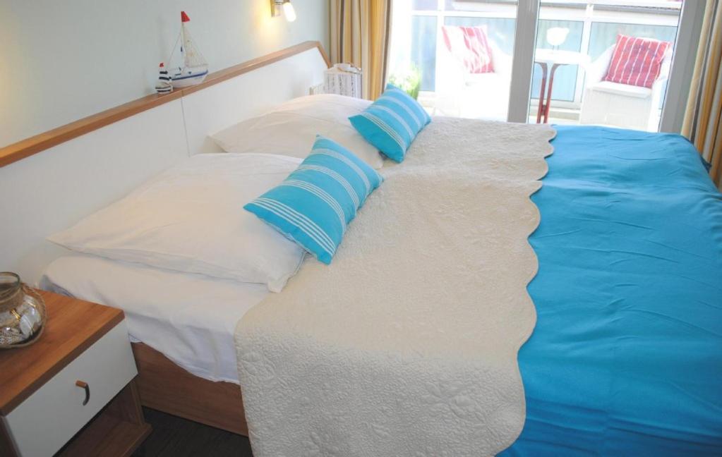 ein Bett mit blauen und weißen Kissen darauf in der Unterkunft Ferienwohnung Yachthafentraum in Kühlungsborn