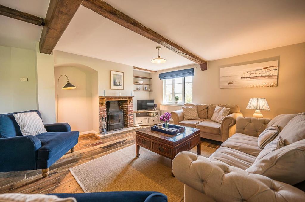 a living room with couches and a fireplace at Drift Cottage, Rendlesham in Rendlesham