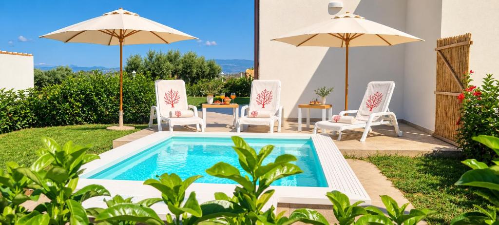 ein Garten mit Pool, Stühlen und Sonnenschirmen in der Unterkunft Corallo Home Resort in Le Castella