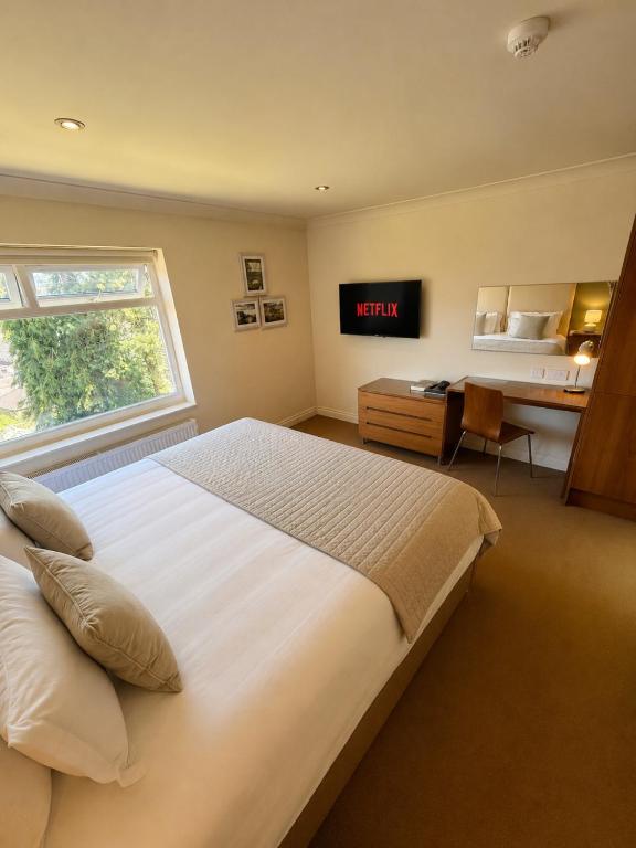 a bedroom with a bed and a desk and a window at Bagshaw Lodge in Bakewell