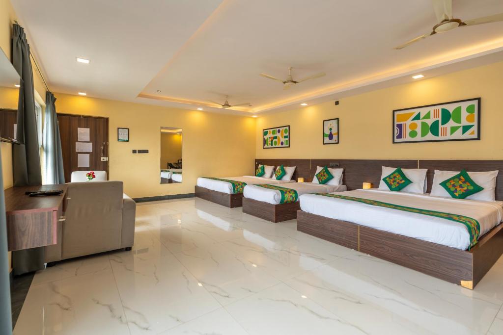a hotel room with two beds and a couch at Treebo Jaguar Comforts, 3 Kms From Mahatma Gandhi Park in Chikmagalūr