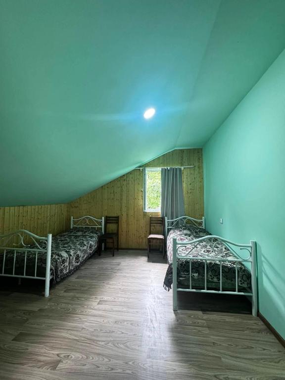 a room with four beds in a room with a blue ceiling at Barisakho Mountain House in Chirdili