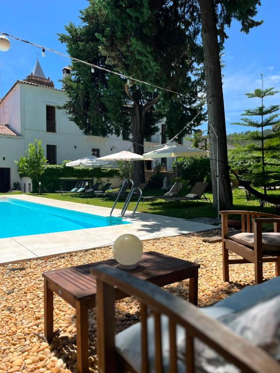 a pool with a table and benches next to a house at HOTEL LUZ ALMONASTER in Almonaster la Real